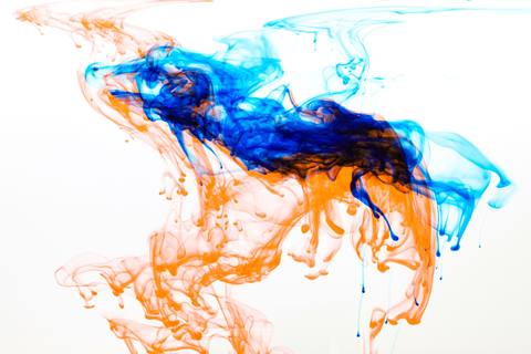 Oranje en blauwe inkt die in water uitvloeit, beeld bij de slimme labels van TECARI.